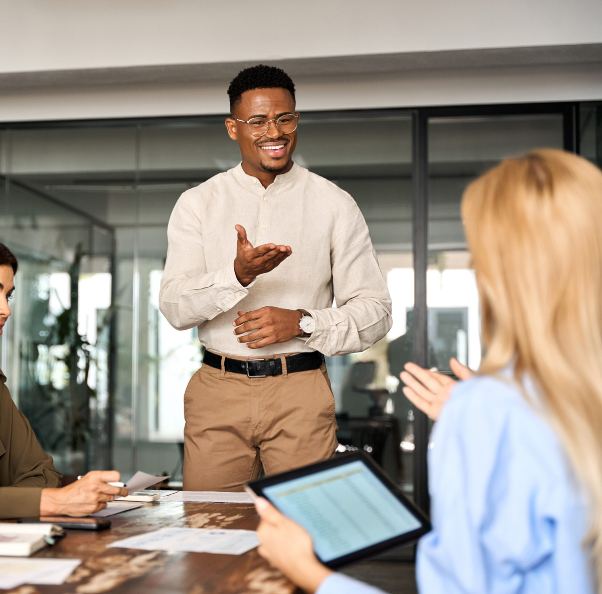 Business professional giving presentation to colleagues at meeting table